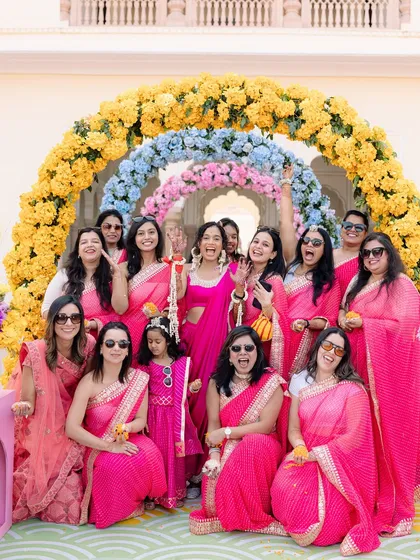 The bride and her squad. A fun and vibrant group photo with the bridesmaids, all dressed in pink, celebrating at a Mehendi or Haldi function.