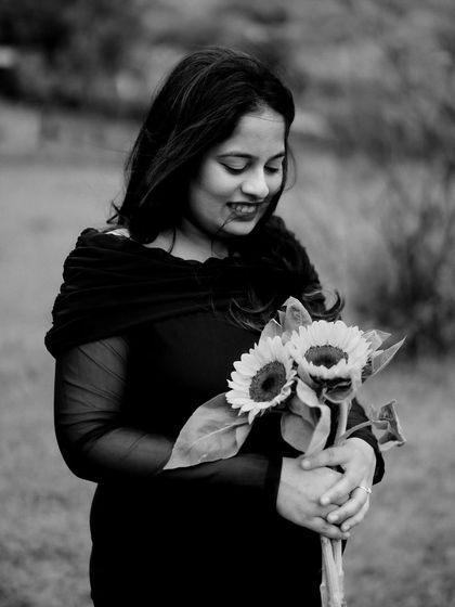 A beautiful black and white close-up of the mom-to-be looking down at her bouquet of sunflowers, a gentle smile on her face.
