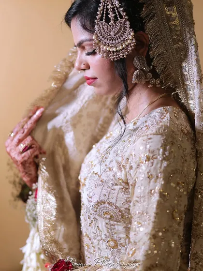 A detailed portrait of the bride, focusing on her intricate side headpiece (passa) and elegant attire.
