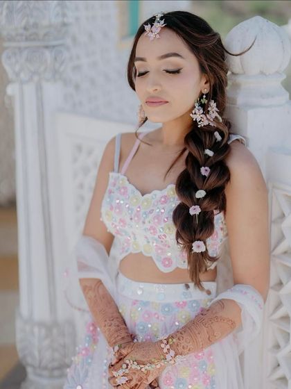 A portrait of bridal beauty. Our bride wears a custom co-ord set with delicate floral appliqué in pastel pinks and blues, perfect for a daytime Mehendi or Haldi ceremony.