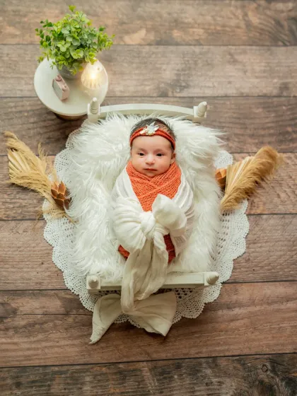 An adorable shot of the baby awake and looking at the camera from the miniature bed setup.