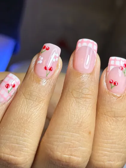 How cute is this? This playful design features hand-painted cherries and flowers over a pink gingham pattern. It’s a perfect example of detailed, custom nail art on shorter, square-shaped nails.