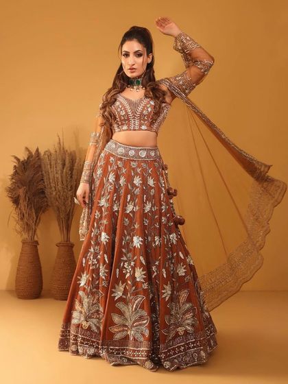 A full-length shot of the model in a stunning rust-coloured lehenga, her look elevated by our choker.