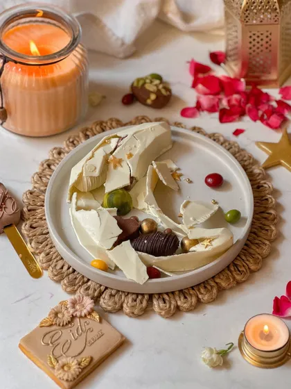 The aftermath of the smash, revealing the delicious assortment of chocolates, pralines, and dates hidden inside the white chocolate moon. It's a treat that's as fun to eat as it is to break.