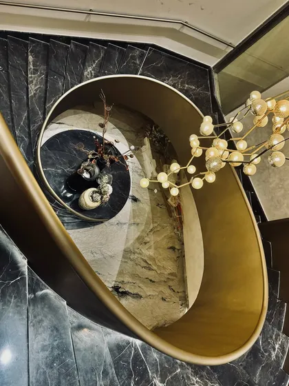 A staircase can be more than just a connection between floors; it can be the heart of a home. We designed this sculptural, spiral staircase with black marble treads and a flowing brass balustrade, turning a functional element into a central piece of art that is dramatic from every angle.