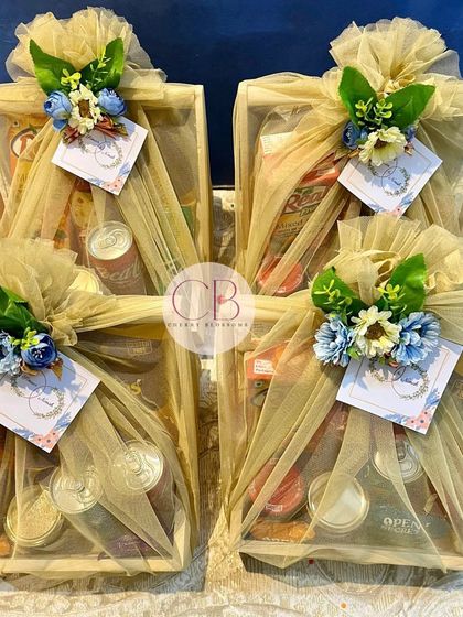 These confectionery hampers were designed as engagement favours. Each pinewood basket is packed with a variety of drinks and snacks, and elegantly wrapped in beige tulle with a floral accent.