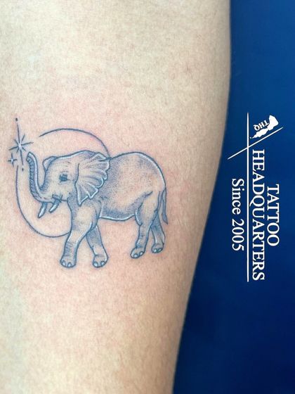 A fine-line elephant tattoo within a crescent moon, with a sparkling star, a whimsical and gentle design.