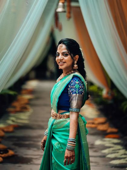 A stunning portrait of a South Indian bride in a vibrant green saree, looking over her shoulder with a beautiful smile.