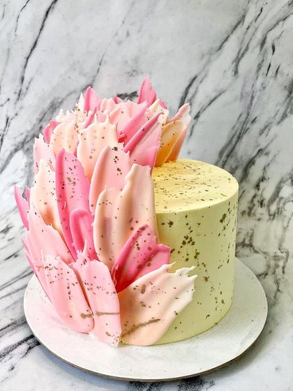 I created this abstract design using colored white chocolate to make feather-like shards. The shades of pink and the splatter of gold dust give it a modern, artistic feel.