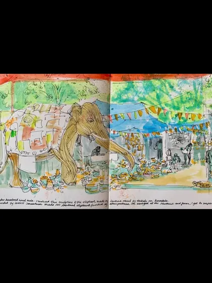 A vibrant, double-page sketchbook drawing of the festival, featuring the iconic elephant installation and the bustling market stalls.