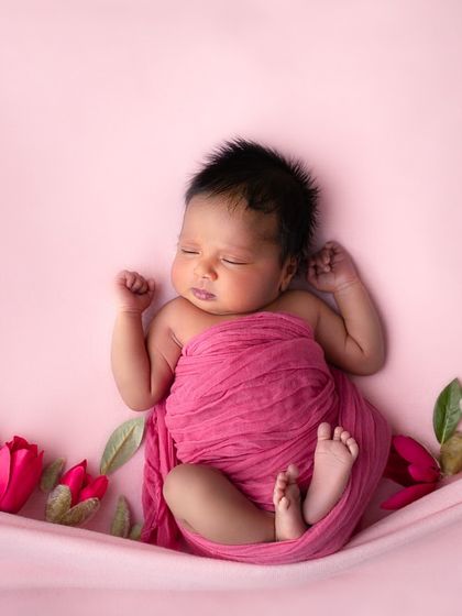 A three-week-old baby yawns while wrapped in a hot pink swaddle. These real, unscripted moments are what make your gallery truly unique and personal.