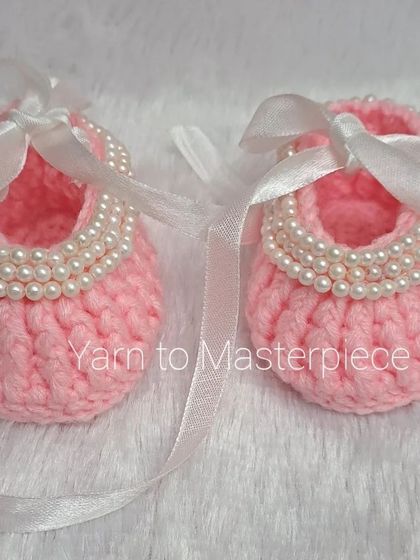 A front view of the pink pearl ballerina booties, tied with a classic white ribbon.