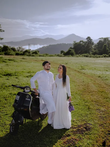 A wide shot capturing the couple, the scooter, and the magnificent mountain range. This is a great example of a destination shoot near Sakleshpur.