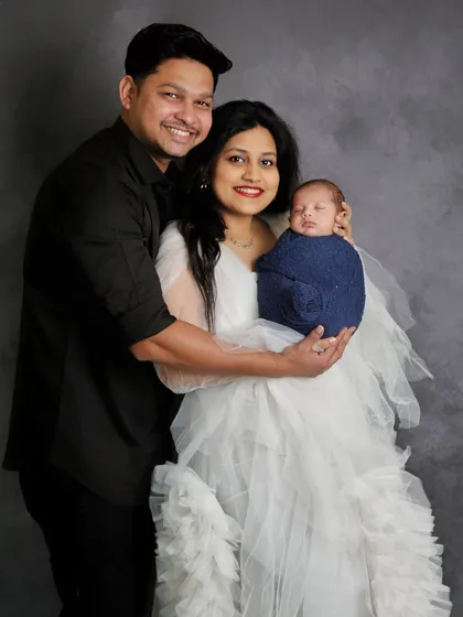 A happy family portrait with the newborn wrapped in a cozy blue swaddle. The parents' smiles reflect the immense joy of welcoming their son.