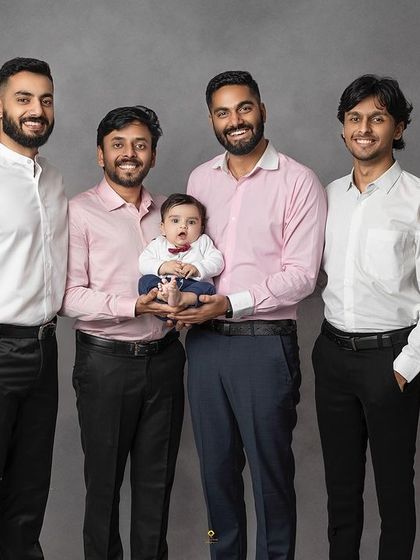 The men of the family proudly holding the newest, smallest member. This portrait showcases the bond between uncles, fathers, and the little one who has captured all their hearts.