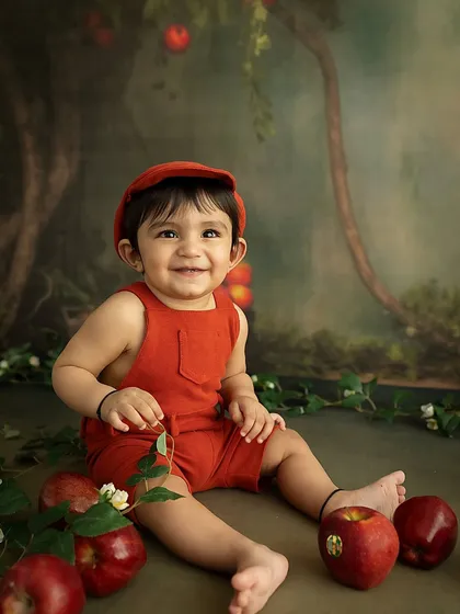 A sweet, smiling portrait of the baby amidst the apples. The painterly backdrop and thoughtful styling create a whimsical, storybook feel.
