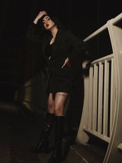 A full-length shot showing the complete look with the blazer, skirt, and knee-high boots.