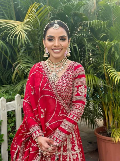 A full-length view of this stunning bride in her red wedding lehenga. The makeup and hair are styled to perfection, creating a look that is both classic and breathtaking.