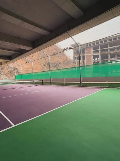 A view of my indoor tennis court from the side, showing the full length of the playing area against the backdrop of the Powai hills. It's a unique setting for a game of tennis.