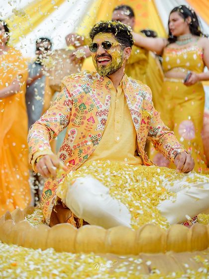 A fantastic shot of the groom being showered with flower petals by his friends and family during the Haldi ceremony.