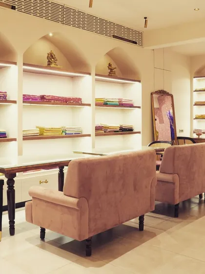The arched display niches are a recurring motif, bringing a sense of classical Indian architecture into the modern retail space. Soft, indirect lighting within the shelves ensures the fabrics are beautifully lit.