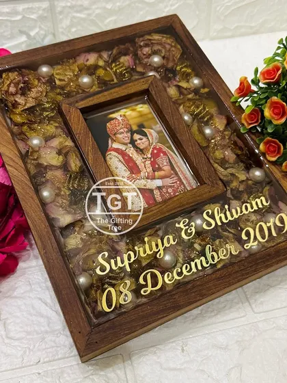 A close-up of an 8x10 inch teakwood frame with lighter-colored preserved roses and pearl accents.