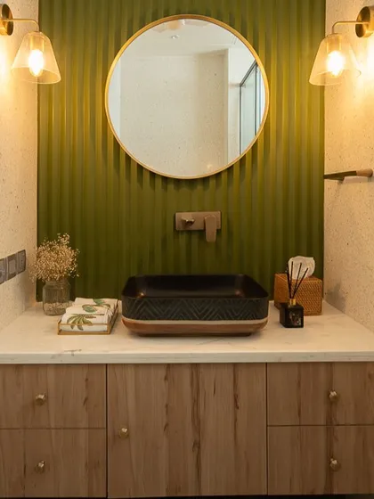 Another vanity from "Project Ivy," this design features a fluted green accent wall and a unique black vessel sink. The round mirror and warm sconce lighting complete the eclectic, modern look.