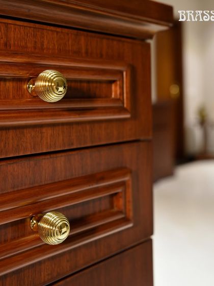 Our Beehive knobs in a Polished Brass finish, installed on the drawers of a rich wooden cabinet. The intricate, reeded design of the knob adds a textural and sophisticated element, elevating the piece of furniture.