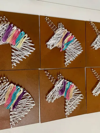 A herd of magical unicorn string art pieces, created by guests at a themed birthday party.