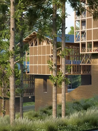 The hotel structure is designed to sit lightly on the hilly terrain. This view from below shows how the building is elevated on a solid base, allowing the natural landscape to flow around and beneath it.