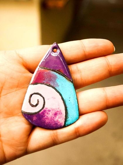 A beautiful enamel pendant with a swirl design, showcasing how different colored glass powders can be blended during firing.