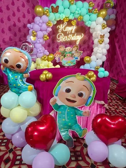 Bachon ki party mein Cocomelon theme aajkal bahut chalta hai. Humne is decoration mein Cocomelon character cutouts, pastel color ke balloons ka arch, aur 'Happy Birthday' neon sign ka istemal kiya hai.
