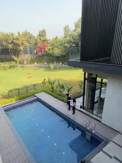 The co-founders stand by the pool at the 'Urban Oasis' project, with the modern, multi-level facade rising behind them. The design showcases extensive use of glass and cantilevered balconies.