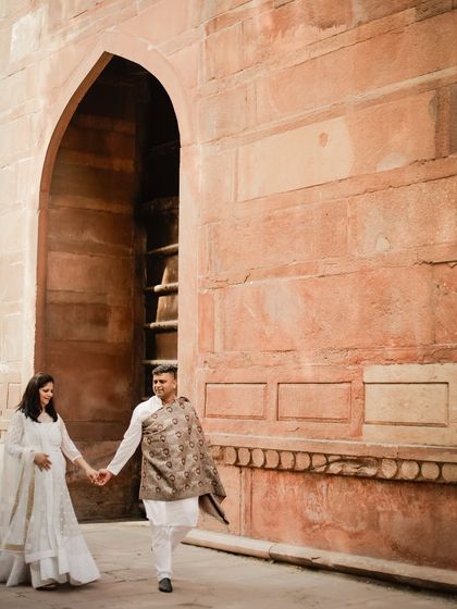 A walk through the historic red sandstone corridors near the Taj Mahal, holding hands and starting their journey together.