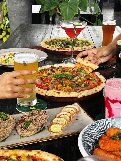 A table full of food and drinks is a table full of happiness. Here you can see a spread of our pizzas, appetizers, beers, and milkshakes, ready for a feast.