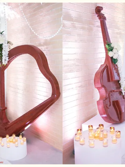 Musical instruments as decor props. A harp and a cello, surrounded by candles and white flowers, add a touch of classical elegance and artistry to this fairytale walkway.