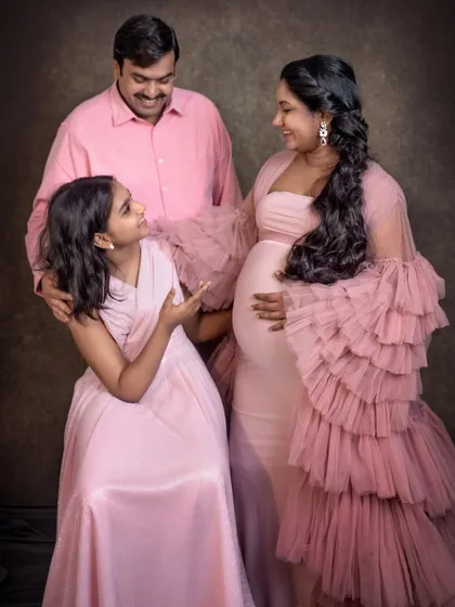 A happy family portrait featuring the popular pink ruffled gown. The older sister's animated expression as she talks to her mother adds a lovely, candid touch to this studio session.