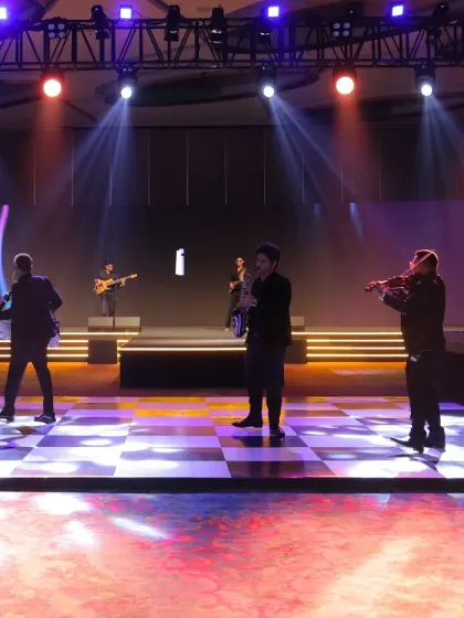 The full band of musicians assembled during a flashmob performance, featuring a saxophonist, violinist, and guitarist engaging the audience.