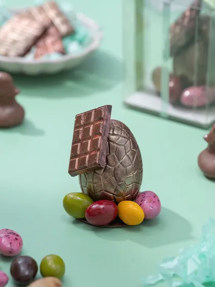 A mini chocolate piñata egg, designed to look like a house with a chocolate bar roof. It's a smaller, individual version of my popular smashable desserts.