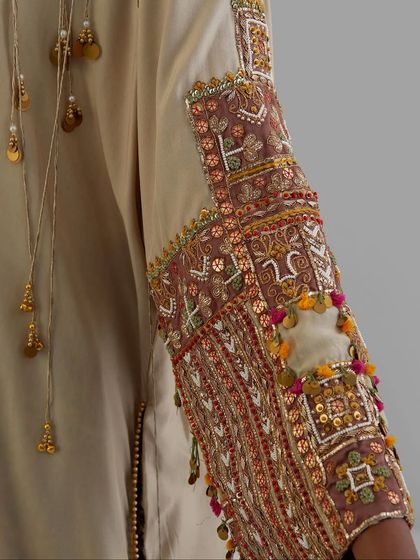 A detailed view of a sleeve adorned with intricate patchwork, tassels, and mirror work, a celebration of traditional crafts.