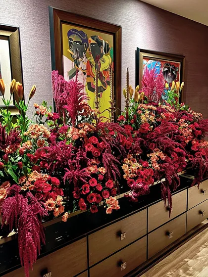 A console table overflowing with a lavish arrangement of red and pink flowers for a festive celebration.