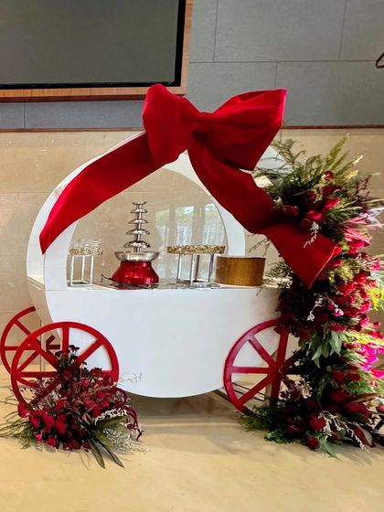 A single treat cart, beautifully decorated with a red bow and a cascade of red flowers.