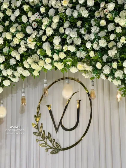 A close-up of the custom "VJ" monogram, beautifully framed by a wreath and set against a clean, white-paneled backdrop.