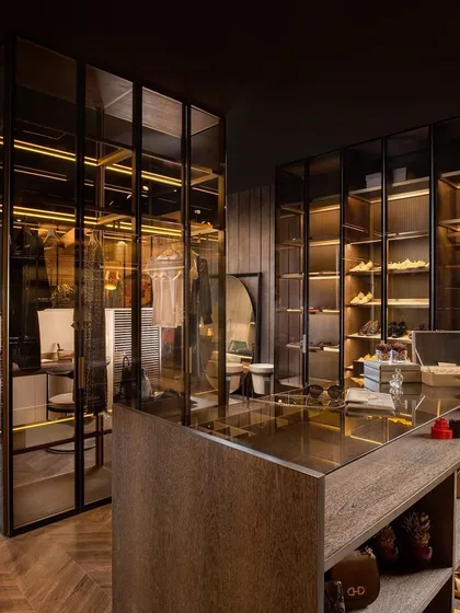 I believe a wardrobe can be more than storage; it can be a centerpiece. This freestanding island wardrobe, crafted from aluminium profiles and tinted glass, acts as a see-through partition between the bedroom and dressing area, creating a truly open and modern layout.