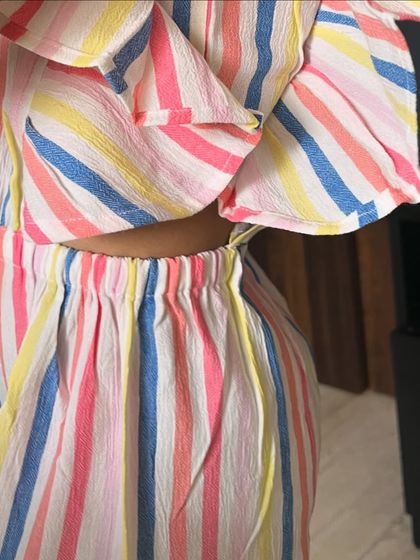 It's all about the details! A close-up of the waist cut-out and soft, textured fabric of our rainbow striped jumpsuit.