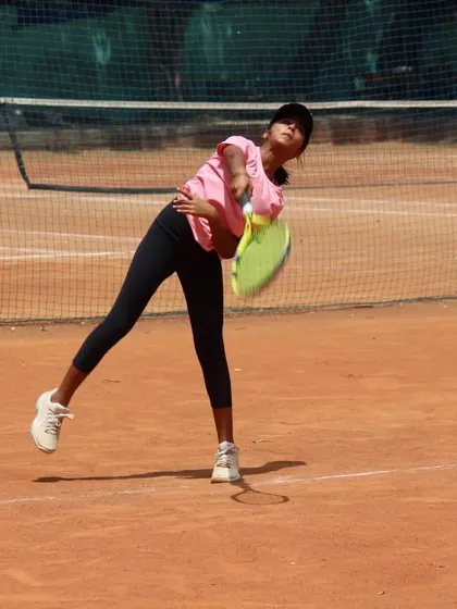 A junior player practicing her service motion. Repetition is the mother of skill.