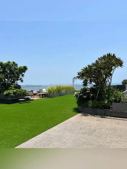 We transform apartment rooftops into exclusive retreats. This terrace garden offers a lush lawn and curated planters, creating a serene escape with an uninterrupted view of the Mumbai skyline and the sea beyond.