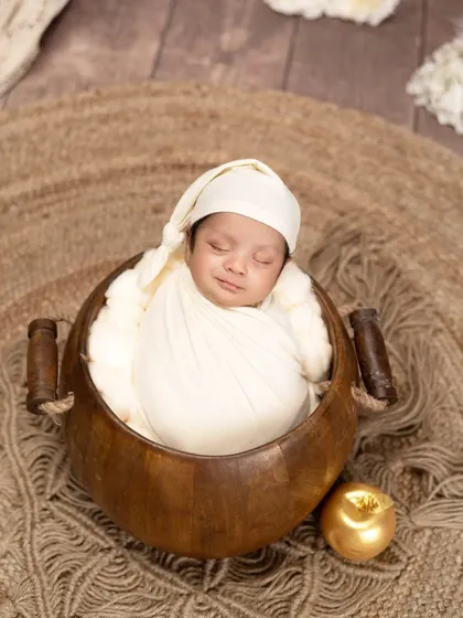A peaceful smile on a sleeping newborn's face. Tucked into a wooden bowl with a golden apple, this portrait is simple, warm, and utterly precious.