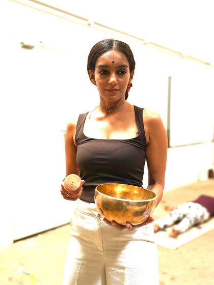 Holding a singing bowl, a key instrument in my sound healing sessions. Each bowl has a unique frequency that helps to balance the body's energy centers, promoting a state of deep calm and mental clarity.