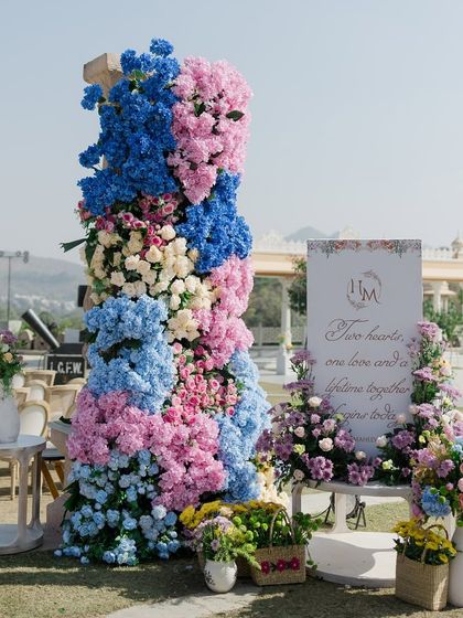 A personalized welcome sign for the wedding ceremony, adorned with a stunning arrangement of pink and blue hydrangeas. This is the first beautiful detail guests see as they arrive.